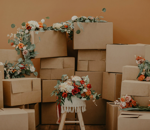 A stack of cardboard shipping boxes with red, white and green florals laid on top of them