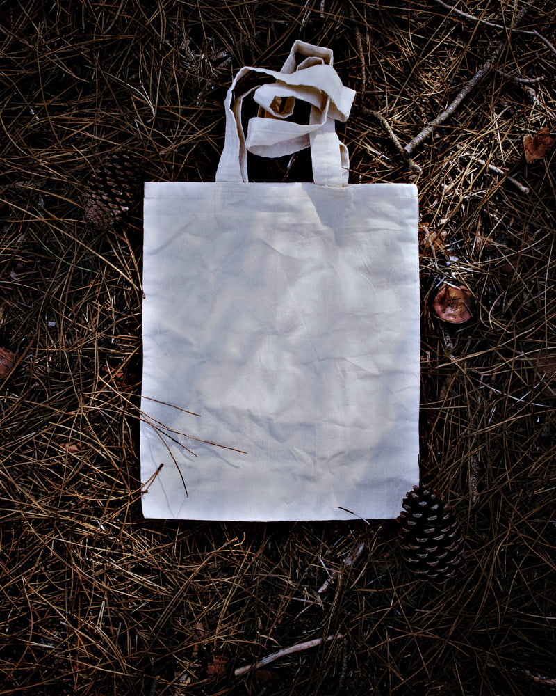 Reusable canvas tote seen from above, laying flat on a patch of grass